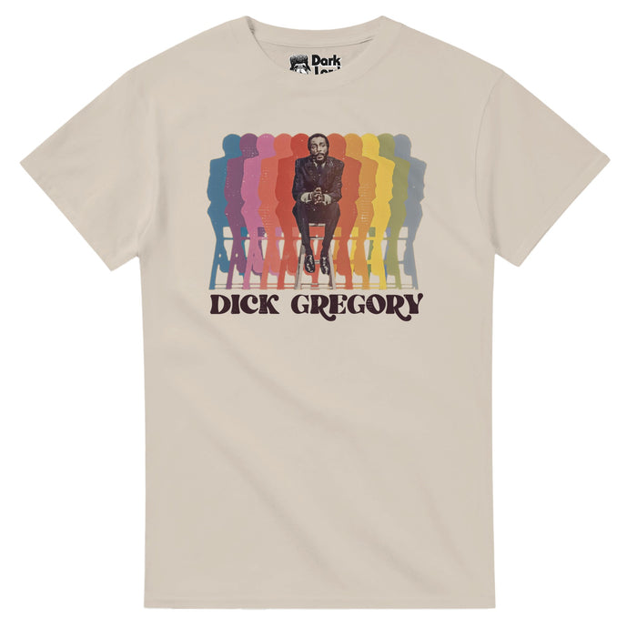 A vintage, sand colored souvenir t-shirt with an image of Dick Gregory sitting on a bench, hands clasped, next to multiple colorful reflections of himself and above his name: "Dick Gregory". In reference to the famous comedian, actor, writer, social critic, and activist against racial injustice and for feminism and animal rights, popular in the 1960s for his comedy and no-holds-barred humor sets, popular across the United States and in the African American community, especially in the Southern U
