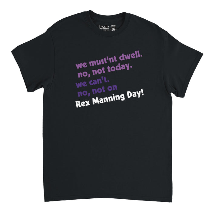 A retro black colored souvenir t-shirt that says "we mustn't dwell. no, not today. we can't. no, not on Rex Manning Day!" The quote is said by character Mark in the iconic cult classic coming of age film "Empire Records", played by famous actor Ethan Embry, referencing the incoming musician Rex Manning coming to see their record store and the day fans continue to celebrate on April 8th to honor the movie and Kurt Cobain.