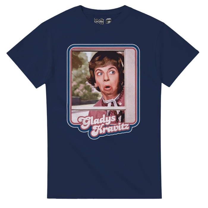 A dark blue short sleeved souvenir retro t-shirt with the graphic of iconic television character Gladys Kravitz peaking through a window, her face shocked into an "O" expression. The picture is outlined by pink and blue lines and the character's name, 'Gladys Kravitz', highlighted in pink text below, referencing the American fantasy sitcom television who Bewitched, popular in the 1960s and 1970s, starring Alice Pearce as the nosy neighbor type.