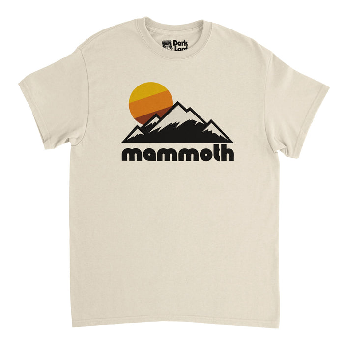 A soft cream colored vintage, 80s style t-shirt that says "mammoth" in bold, black bubble letters underneath the image of multiple snow covered mountain peaks, an aesthetic yellow/orange/reddish brown sun setting. In reference to California's Mammoth Mountain, home to Mammoth Mountain Ski Area and ski and snowboard resort, located in the stunning Sierra Nevada Range with incredible mountain views, hiking and backpacking opportunities, and winter sports.