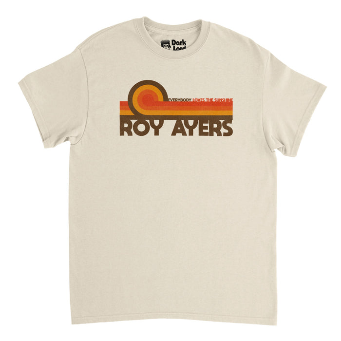 A soft cream colored vintage, 90s style t-shirt that says "Roy Ayers" in brown letters, referencing the famous R&B and jazz singer who revolutionized jazz-funk and was key in the acid jazz movement, nicknamed the "Godfather of Neo Soul". Above his name are multicolored stripes - red, orange, yellow and brown - and the title of his most famous album: Everybody Loves The Sunshine.