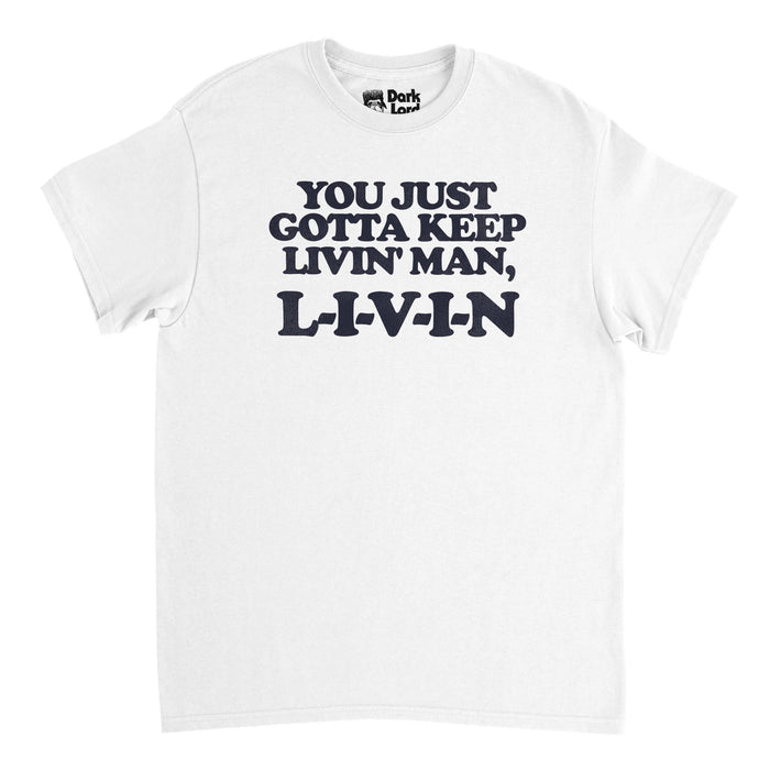 A vintage, 70s style white colored t-shirt that says "You just gotta keep livin' man, L-I-V-I-N". References the iconic line said by character David Wooderson, played by Matthew McConaughey, from famous 1993 comedy movie Dazed and Confused. starring Jason London as Randall "Pink" Foyd, Joey Lauren Adams, Milla Jovovich, and Shawn Andrews.