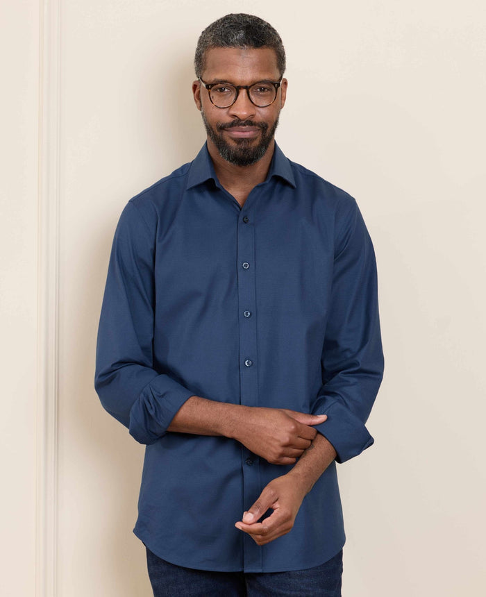 Man wearing a blue shirt against a beige wall