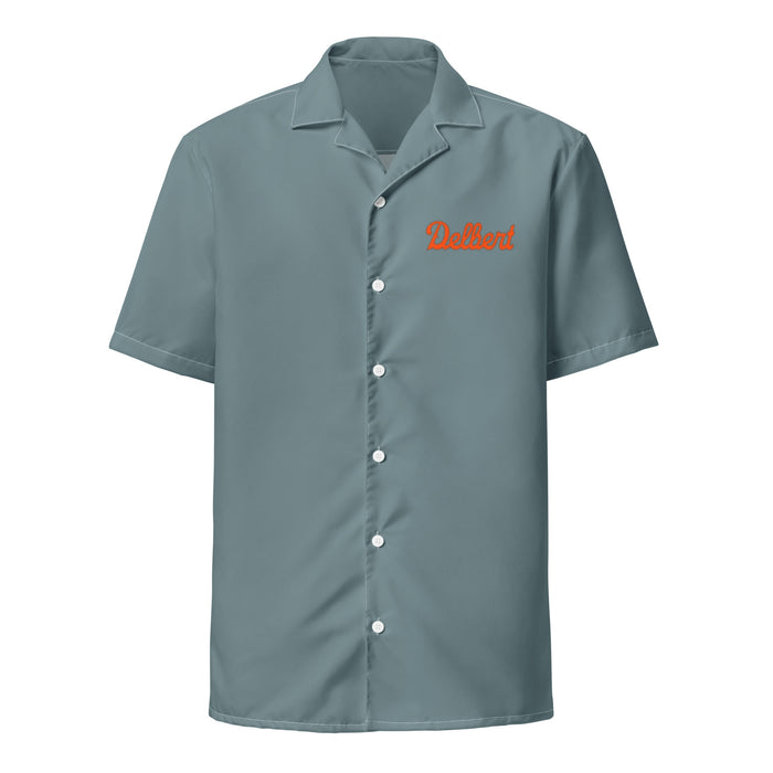 A vintage, 70s style collared, button up sea green/gray colored costume shirt with short sleeves that says "Delbert" on the front left side in orange cursive letters. References the shirt worn by Delbert McClintock, a spider exterminator in the famous horror and comedy film "Arachnophobia", played by iconic actor John Goodman.