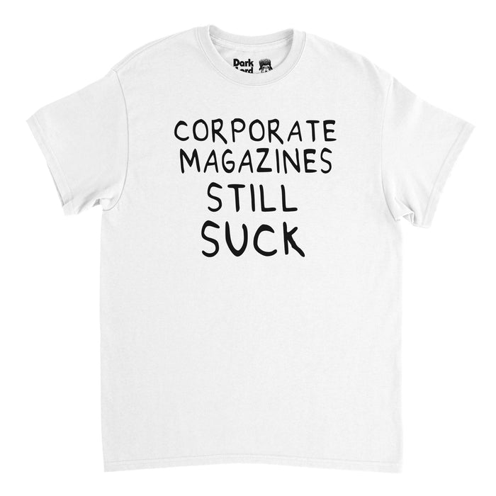 A retro, 80s style white colored t-shirt that says "Corporate Magazines Still Suck" in black, handwritten letters. References the iconic shirt Kurt Cobain wore on the 1992 cover of Rolling Stone magazine that featured the iconic alternative rock, grunge band Nirvana after the release of their album "Nevermind".