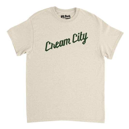 A retro, 80s style soft cream t-shirt that says "Cream City" in dark green text, in reference to the nickname given to Milwaukee, Wisconsin in honor of its light colored bricks made of clay and one of the colors of legendary NBA basketball team the Milwaukee Bucks.