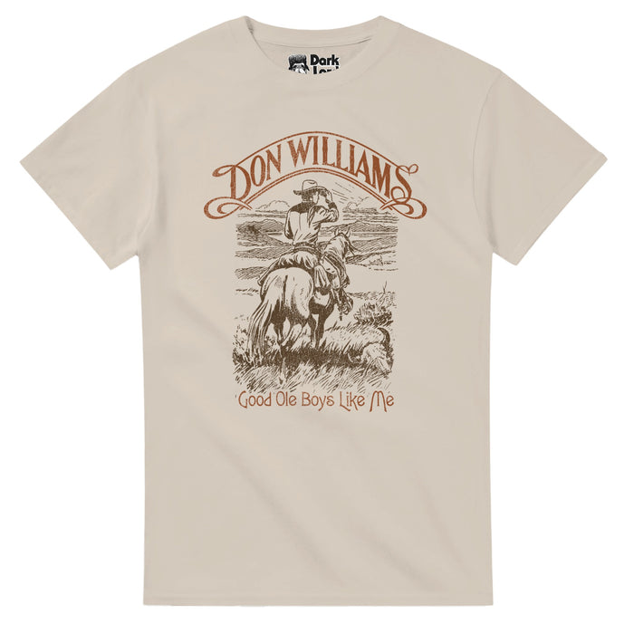 A retro, sand colored 80s style short sleeved t-shirt that says Don Williams in brown letters surrounded by swirls and "Good ole Boys Like Me" with a black and white image of a man with a cowboy hat riding a horse in the grasslands. References the iconic 1979 song written by Bob McDill and recorded and sung by country music singer Don Williams on the album Portrait.
