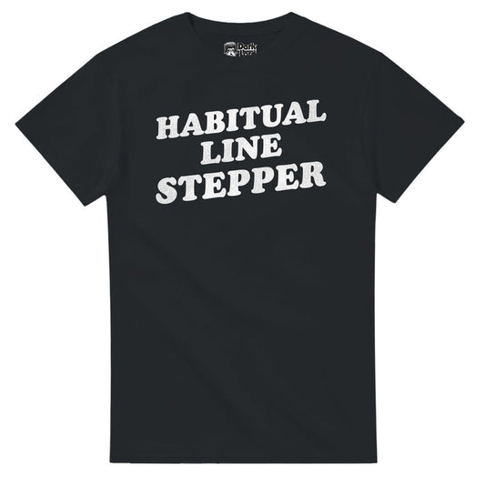 A retro, 70s style black colored short sleeved t-shirt that says "Habitual Line Stepper" in white bold text in reference to the comedy sketch Chappelle's Show created by comedians Dave Chappelle and Neal Brennan, specifically the Charlie Murphy sketch as he talks about Rick James.