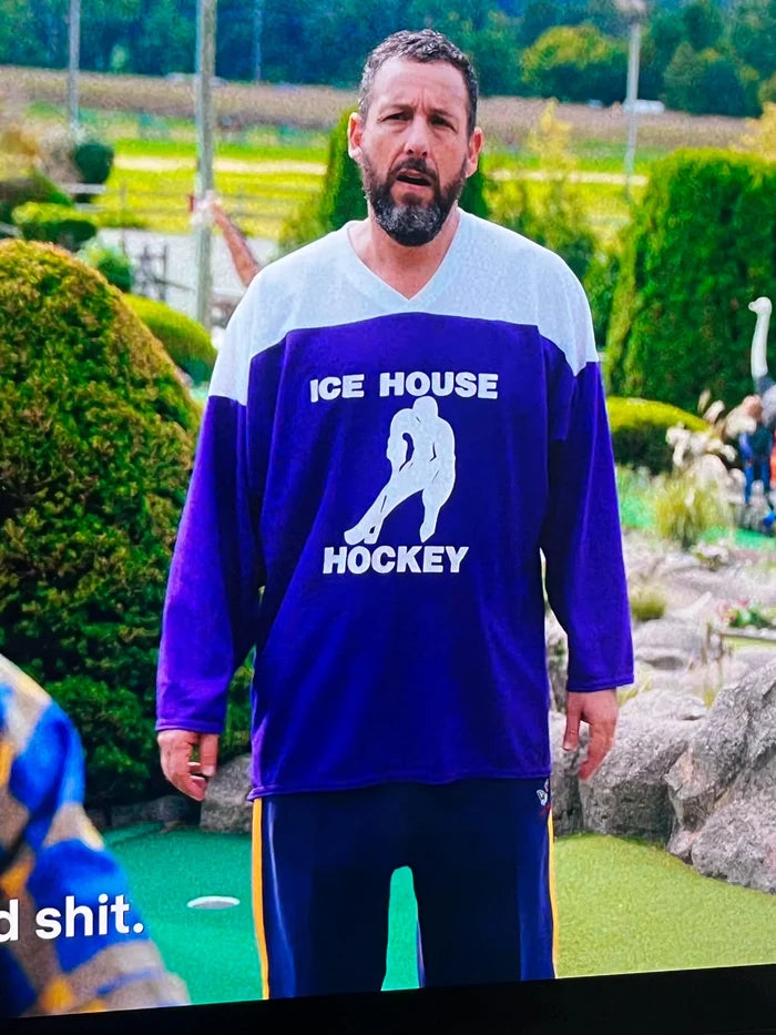 Adam Sandler wearing a white and purple, retro "Ice House Hockey" jersey with the image of a man playing hockey during the sports comedy film "Happy Gilmore 2" as tribute to the late NHL player Johnny Gaudreau as the jersey had the number 13 on it.