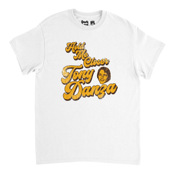 A vintage, souvenir 80s style t-shirt in the color white that says "Hold Me Closer, Tony Danza" referencing the often misquoted line "Hold me closer, tiny dancer" from the hit song "Tiny Dancer" by iconic musician Elton John, popularly misquoted by character Phoebe, played by actress Lisa Kudrow, in the comedic television series "Friends". Includes an image of the head of Tony Danza in the color yellow, a famous retired professional boxer and actor.