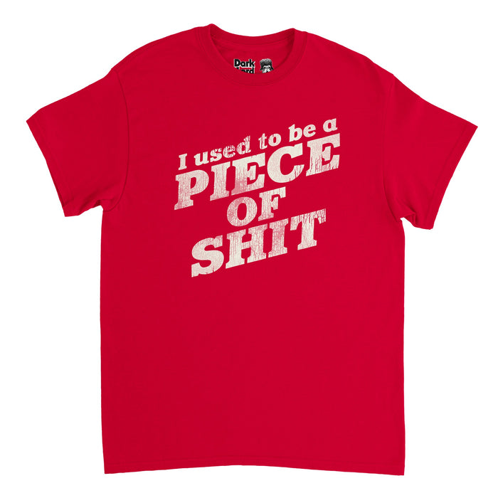 A red colored vintage 70s style t-shirt that says the quote "I used to be a PIECE OF SHIT", referencing the episode "Baby Cries" in the television comedic series "I Think You Should Leave with Tim Robinson" which was created by Tim Robinson and Zach Kanin; the full saying is "I used to be a piece of shit. Slicked back hair, sloppy steaks at Pyloon’s. You would have not liked me back then."
