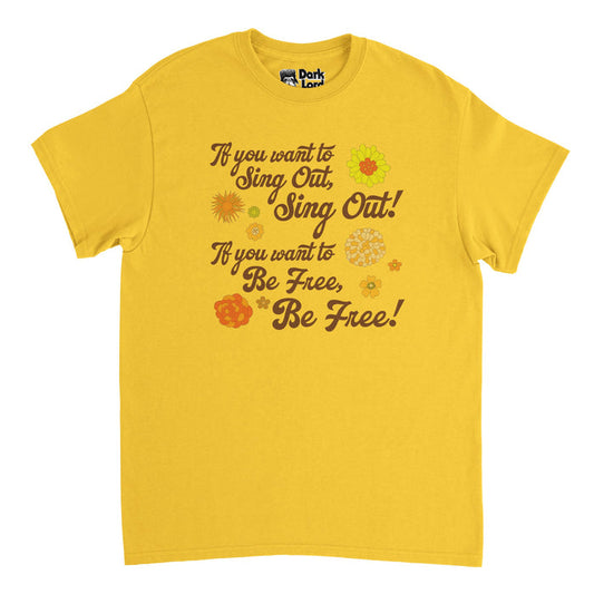 A retro, souvenir yellow t-shirt that says "if you want to sing out, sing out! If you want to be free, be free!" Surrounded by brightly colored flower drawings and references lyrics from the folk rock song "If You Want to Sing Out, Sing Out" by Yusuf / Cat Stevens, a famous British singer and songwriter