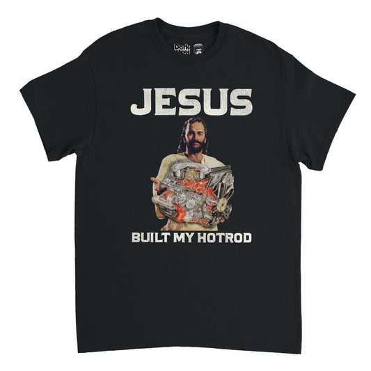 A retro, black colored short sleeved 80s style t-shirt that says JESUS BUILT MY HOTROD in all caps with an image of a man with a beard and long brown hair, resembling Jesus, holding a hotrod, a red and silver engine, in his hands. References the iconic 1991 song "Jesus Built My Hotrod" by industrial metal band Ministry from their famous album Psalm 69: The Way to Succeed and the Way to Suck Eggs.