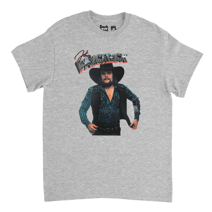 A retro heather gray colored short sleeved 1980s style t-shirt that says Johnny Paycheck, the word "Paycheck" made of bubble letters with pictures of city scenery inside. Includes an image of the iconic country singer songwriter wearing a blue button up plaid flannel with a vest on top and a classic cowboy hat, famous for heading up the outlaw movement with famous songs like "Take This Job and Shove It", "She's All I Got", and "Colorado Kool-Aid".