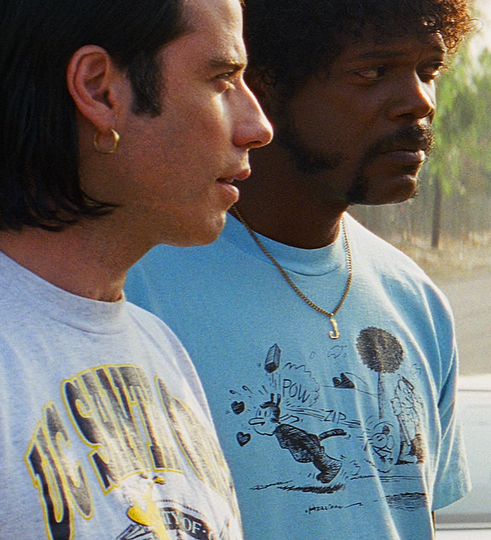 Vincent Vega played by John Travolta and Jules Winnfield played by Samuel L. Jackson, one wearing a UC Santa Cruz shirt and the other a light blue shirt that says 'pow' and 'zip' with cartoon character graphics standing side by side from the classic action thriller movie "Pulp Fiction".