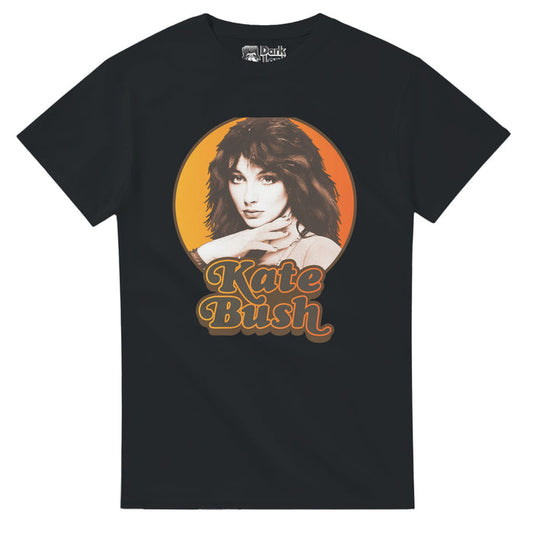 A vintage black colored 80s style t-shirt that says "Kate Bush" in gray text underneath an image of the iconic singer and songwriter looking straight at the camera, her hair dark brown, her hand on her neck, against an hombre yelllow/orange background. References the English singer, dancer, and producer known for her eclectic music style, popular in the 1980s-1990s with 25 UK top 40 singles and hits like "Running Up That Hill", "The Man with the Child in His Eyes",  "Babooshka", and "There Goes