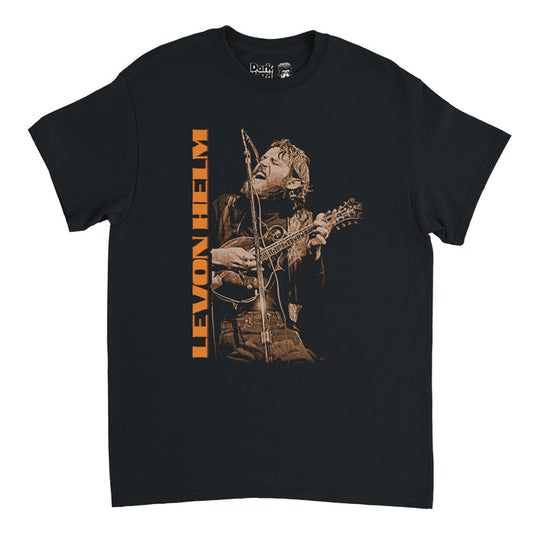 A retro, black short sleeved 80s style t-shirt that says Levon Helm in block orange letters facing sideways beside an image of the iconic musician and drummer, Mark Levon Helm, playing guitar and singing into a microphone onstage.