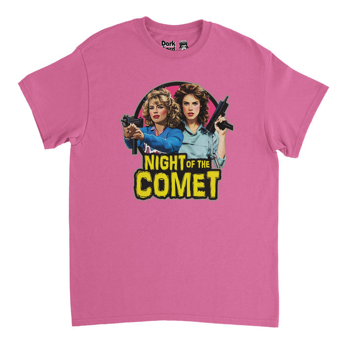A pink, vintage, 80s style t-shirt that says "NIGHT OF THE COMET" in scary, yellow text and includes an image of the two heroines of the film - Samantha Belmont and Regina Belmont - holdings guns wearing blue shirts with big blonde and brunette blowouts against a backdrop of pink. References the famous horror comedic science fiction movie from 1984 in which the heroines, played by Kelli Maroney and Catherine Mary Stewart, fight zombies after a comet.