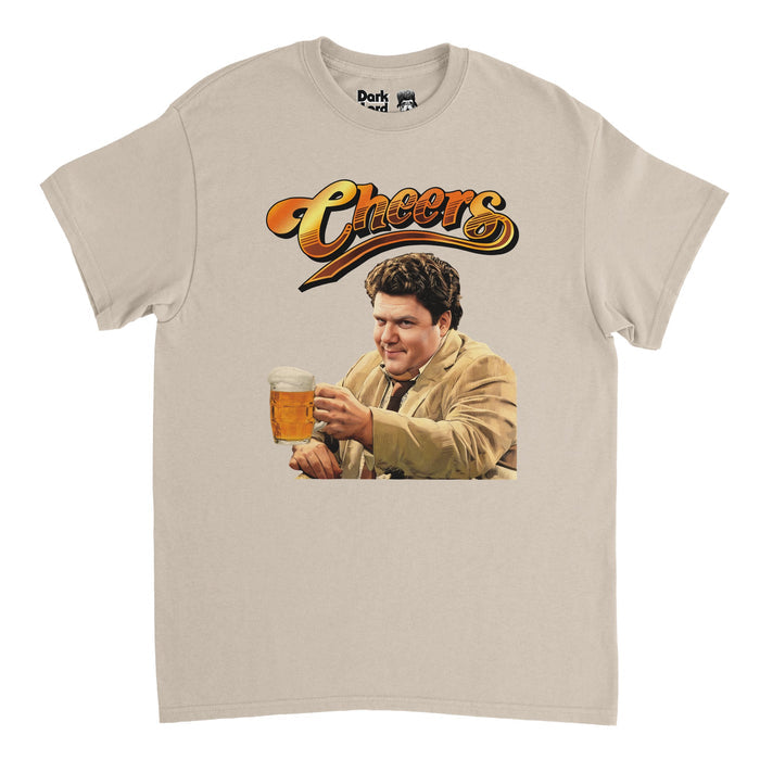 A light brown, sand colored vintage retro short sleeved shirt centering famous actor George Wendt as hilarious character Norm Peterson, wearing a light brown trench coat, a dark brown tie, smiling, holding a beer mug filled to the top, under the line "Cheers" underlined and shaded in yellows and oranges, in reference to the sensational 1980s comedy sitcom television series.