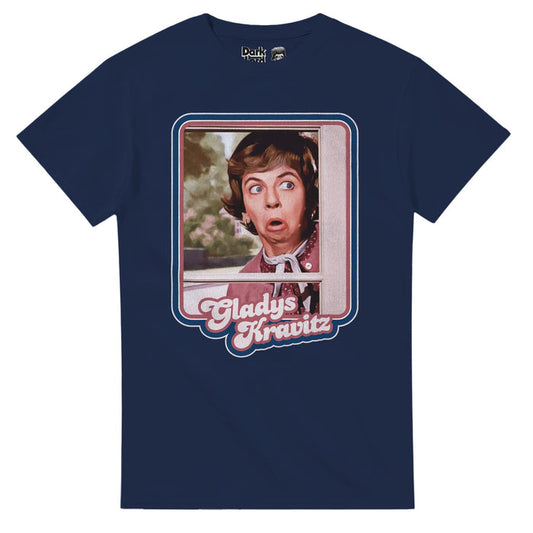 A dark blue short sleeved souvenir retro t-shirt with the graphic of iconic television character Gladys Kravitz peaking through a window, her face shocked into an "O" expression. The picture is outlined by pink and blue lines and the character's name, 'Gladys Kravitz', highlighted in pink text below, referencing the American fantasy sitcom television who Bewitched, popular in the 1960s and 1970s, starring Alice Pearce as the nosy neighbor type.