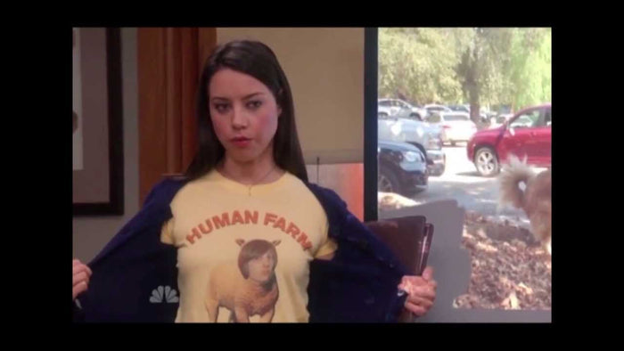 A woman wearing a yellow t-shirt with a graphic of a sheep and the text "HUMAN FARM", referencing the character April Ludgate, played by legendary actress Aubrey Plaza, from the comedic sitcom television series Parks and Recreation.