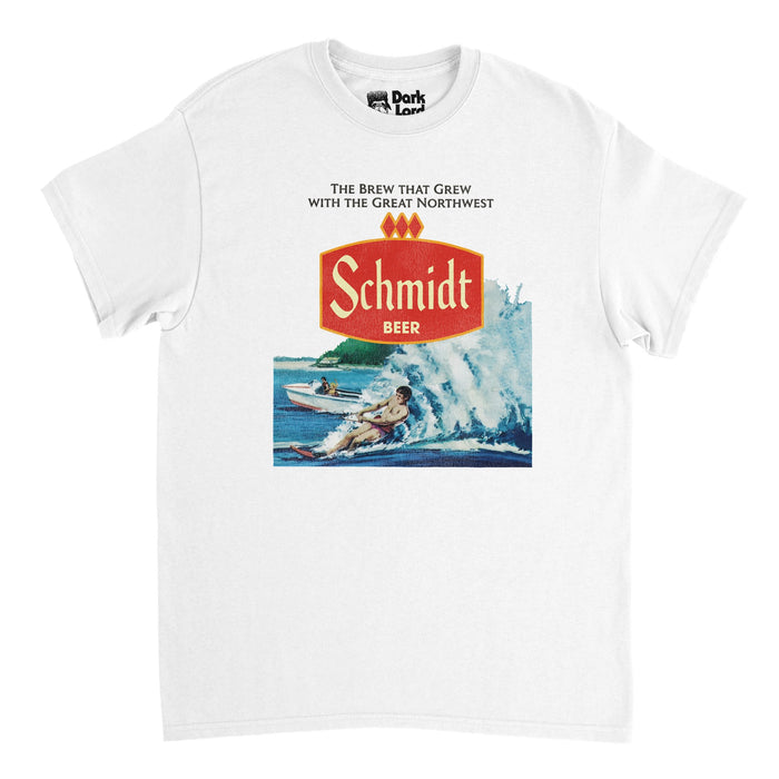 A retro, 70s style t-shirt in white that says "Schmidt Beer" in reference to the Minnesota beer brewing company's red logo, with the company's slogan "the brew that grew with the great northwest". Has an image of a pristine blue lake with a guy waterskiing, connected to a motorboat, in reference to the vintage water skiing design on the retro Schmidt Beer Can Nature Series.