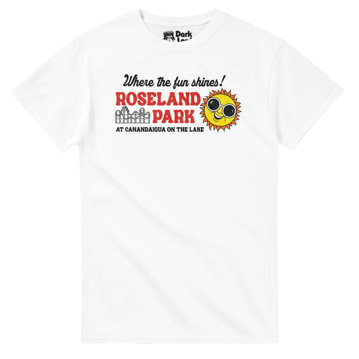 A retro, vintage t-shirt in the color white that says "Where the fun shines! Roseland Park, at Canandaigua on the lake" next to an image of a black and white rollercoaster and a yellow and orange sun with sunglasses smiling. References the amusement park with the slogan "Playground of the Finger Lakes" in new York originally named "Lakeside Park" which was popular from 1925 until it closed in 985.
