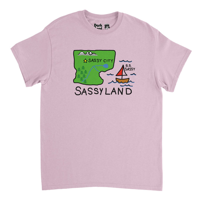 A retro, light pink colored 80s style t-shirt with the image of a map of "Sassyland" with a green piece of land with trees, rivers, a lake, and some mountains, and a yellow star marking "Sassy City" next to a body of water with a red/white sailboat called "S.S. Sassy". References the map shown on the SNL comedy skit 'Sassy's Sassiest Boys' where Sassy Magazine's Phil Hartman (played by Russel Clark) interviews Christian Slater, Joey Lawrence played by Mike Myers, and Andrew McCarthy played by Ja