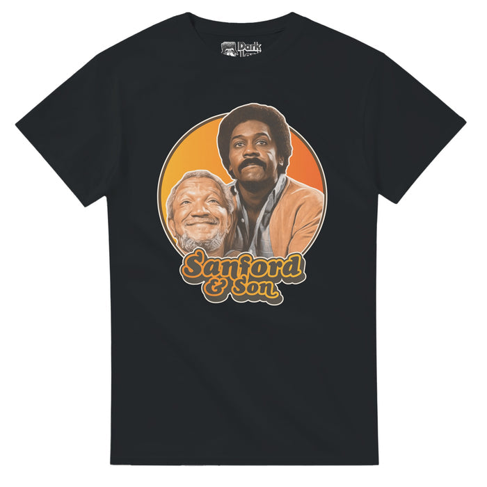 A 70s style souvenir black colored t-shirt that says "Sanford & Son" in orange and gray text underneath an image of iconic characters Fred G. Sanford and Lamont Sanford, played by actors Redd Foxx and Demond Wilson against an hombre yellow and orange background. References the 1972 hilarious sitcom television series "Sanford and Son" also starring Whitman Mayo, LaWanda Page and Don Bexley, based on the British sitcom "Steptoe and Son".