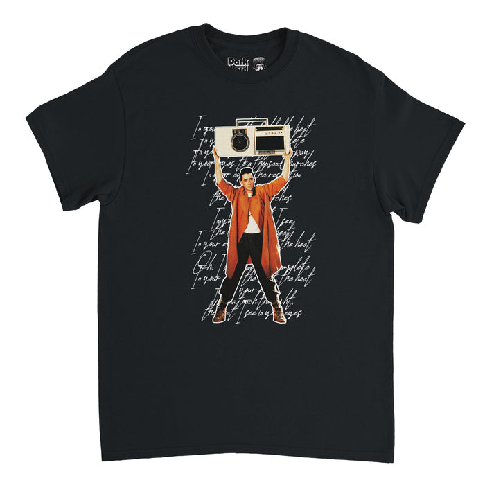 A retro, 80s style black colored t-shirt with the image of a man standing in a bright orange signature trench coat and black pants and boots, holding a boombox over his head, pasted over cursive lyrics in white of the song "In Your Eyes" by Peter Gabriel. References the movie "Say Anything..." in which this song plays as actor John Cusack, playing Lloyd Dobler, holds up a boombox outside the bedroom window of Diane, played by Ione Skye.