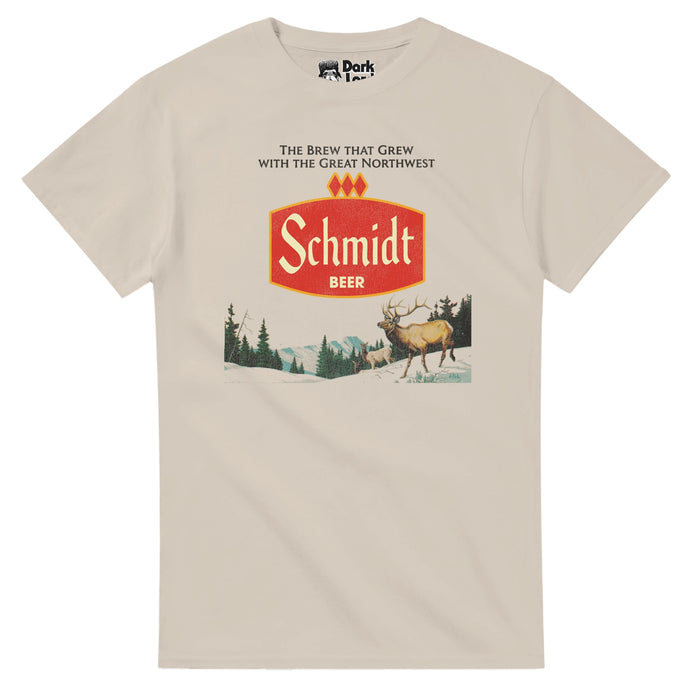 A retro, sand colored 70s style t-shirt that says "The Brew That Grew With The Great Northwest" and "Schmidt Beer" on a red logo above an image of multiple deer, one with huge antlers, walking on snowy hills, a pine tree forest and mountains in the distance. References the Minnesota born macro beer brewery and company that marketed with images of the wilderness of America and had scenic can art and slogans including "the same great beer every time" and was eventually sold to Pabst Brewing Compan