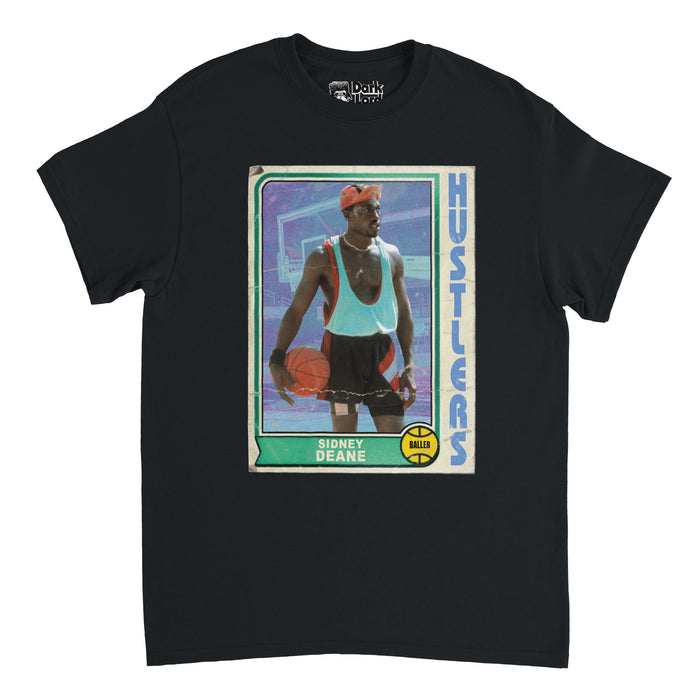 A vintage, souvenir black t-shirt that says Sidney Deane on a green background and Hustlers in blue next to an image of the character Sidney Deane holding an orange basketball on a court, a basketball hoop behind him, with the graphic of a basketball with the word "Baller" written on it below. In reference to the sports comedy film "White Men Can't Jump" starring Wesley Snipes (on the shirt) and Woody Harrelson.