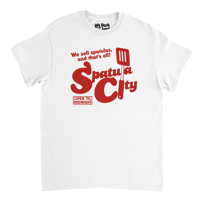 A retro, souvenir white t-shirt that says "We sell spatulas, and that's all!" and "Spatula City" with the graphic of a large spatula filling in for some of the letters and the catch phrase "Open 'Til Midnight". References the 1989 song "Spatula City" by "Weird Al" Yankovic used in the film called "UHF".
