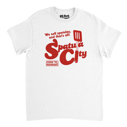A retro, souvenir white t-shirt that says "We sell spatulas, and that's all!" and "Spatula City" with the graphic of a large spatula filling in for some of the letters and the catch phrase "Open 'Til Midnight". References the 1989 song "Spatula City" by "Weird Al" Yankovic used in the film called "UHF".