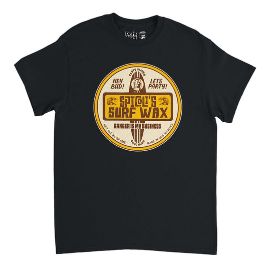A souvenir, vintage short sleeved t-shirt in the color black with a circular yellow toned graphic with the image of a surfboard, Jeff Spicoli's face plastered on the front, on top of which says "Spicoli's Surf Wax" next to ocean waves & "Danger is my Business". Shirt says 'Hey Bed!', 'Cool Buzz', 'Let's party!', 'Made in Los Angeles', & 'Net WT 85 Grams' in reference to the 1982 coming of age comedy film "Fast Times at Ridgemont High" and Sean Penn who played Spicoli.