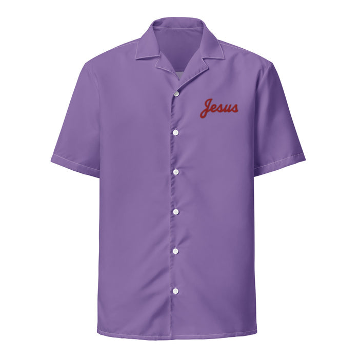 The front of a purple colored, button up, collared retro souvenir shirt that says "Jesus" in red, cursive letters on the top. References the character Jesus Quintana, played by actor John Turturro, in the comedic movie "The Big Lebowski", as he wears a purple bowling jumpsuit to go bowling.