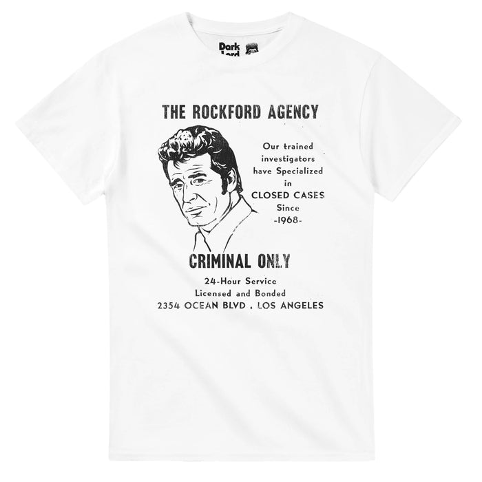 A vintage, 70s style white colored souvenir t-shirt that says "The Rockford Agency, Our trained investigators have Specialized in Closed Cases since 1968, Criminal Only, 24 Hour Service, Licensed and Bonded, 2354 Ocean Blvd, Los Angeles." Includes an image of the iconic LA private investigator Jim Rockford, played by James Garner, who starred in the detective drama television show "The Rockford Files".