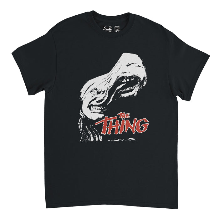 A retro, 80s style black colored t-shirt that says "The Thing" in shaking red lettering underneath the image of a terrifying, shapeshifting creature, seemingly with two heads. References the 1982 horror science fiction film "The Thing" directed by John Carpenter and written by Bill Lancaster, based on the John W. Campbell novella called "Who Goes There?"