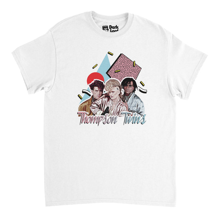 A retro, short sleeved white colored t-shirt that says "Thompson Twins" in hombre pink to light blue colors underneath an image of three people - Alannah Currie, TomBailey, and Joe Leeway - in front of graphics of shapes like a red circle, blue triangle, and pink square, confetti falling around them. References the popular UK pop band that created hits like 'Hold Me Now,' 'Lay Your Hands on Me,' and 'King for a Day'.
