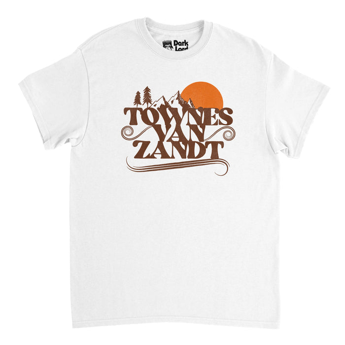 A retro short sleeved white t-shirt that ays "Towns Van Zandt" with swirls coming out of the letters underneath the image of a couple beautiful mountain peaks next to a setting orange sun and some pine trees. References the American singer and songwriter John Townes Van Zandt with popular hits like Panchy and Lefty, Snake Mountain Blues, and If I Needed You.