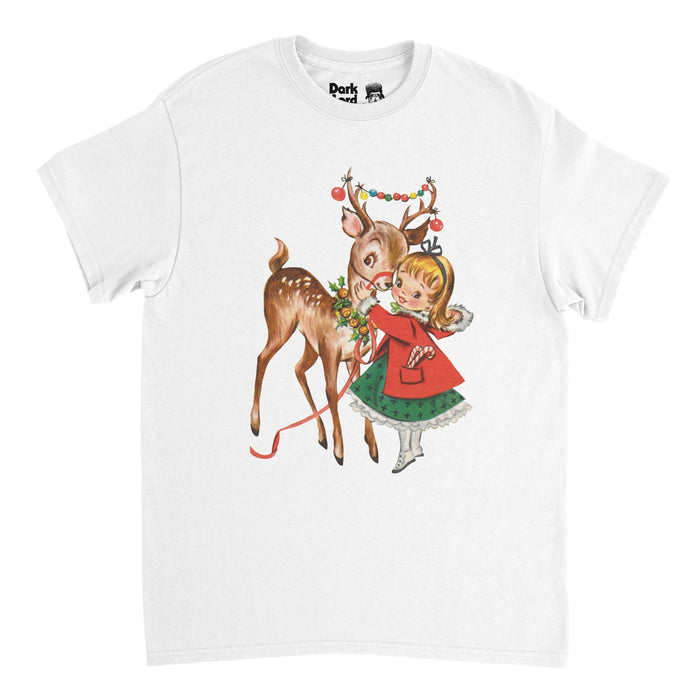 A retro, 80s style white colored t-shirt with the image of a small doe eyed deer with antlers and ornaments hanging in between, wearing a wreath, next to a young blonde haired girl with a green ribbon in her hair, a bright red fur coat, a green dress, and little white shoes, a retro Christmas gift art print.