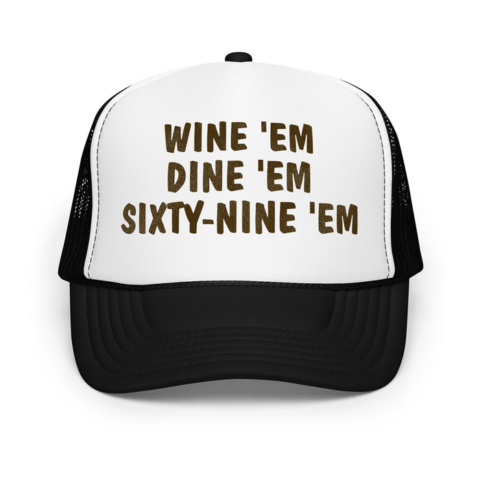 A retro, souvenir white and black foam trucker hat and costume with the words "Wine 'Em Dine 'Em Sixty-Nine 'Em" on the front in bold black letters. References the iconic hat made famous by the character Sea Bass, played by legendary NHL hockey player and actor Cam Neely, which he wore in the movie "Dumb and Dumber".