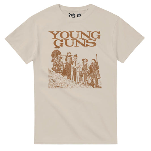 A sand colored, light brown Young Guns retro 80s style t-shirt with an image of six guys posed on the side of a New Mexico desert hill with cowboy hats and boots, some wielding guns. In reference to the iconic retelling of Billy the Kid and the Regulators from the Lincoln County War in the 1988 western film "Young Guns" starring iconic actors Emilio Estevez, Kiefer Sutherland, Lou Diamond Phillips, Charlie Sheen, Dermot Mulroney, and Casey Siemaszko.